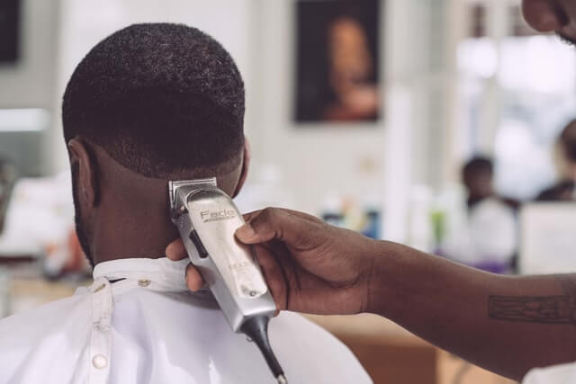 Salon management app user Barber is shaving customers hair.