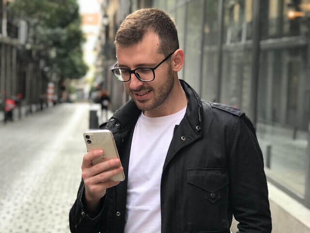 A man is using Barber appointment software at his mobile phone on the street.