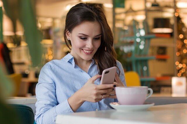 A woman is using Spa management app at her mobile phone and smiling.