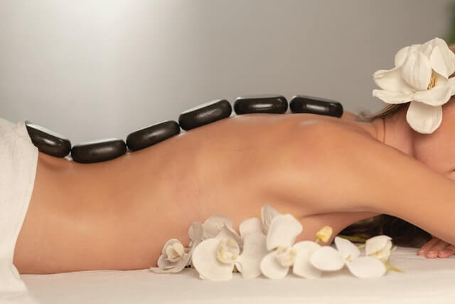 Salon software user Woman is lying face down naked with spa stones on her back.