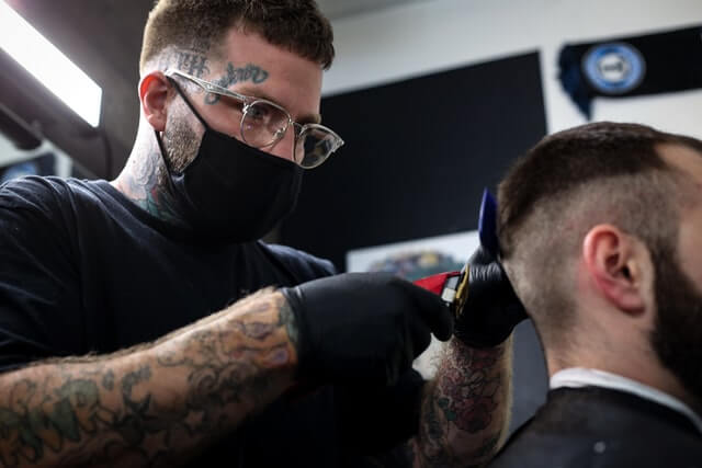 A Barber booking app user barber is shaving his customer's hair.